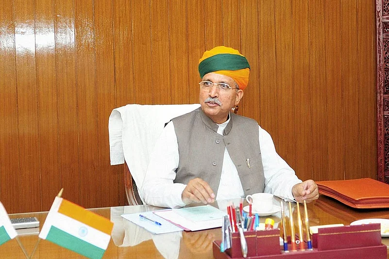 Shri Arjun Ram Meghwal seated at an official desk with the national flag.